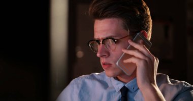 karanlık ofisinde cep telefonu kullanan adam