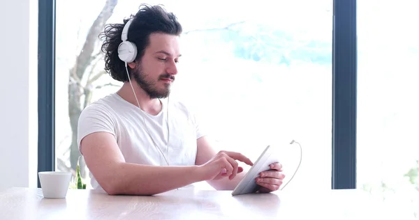 Молодий чоловік слухає музику на планшеті вдома — стокове фото