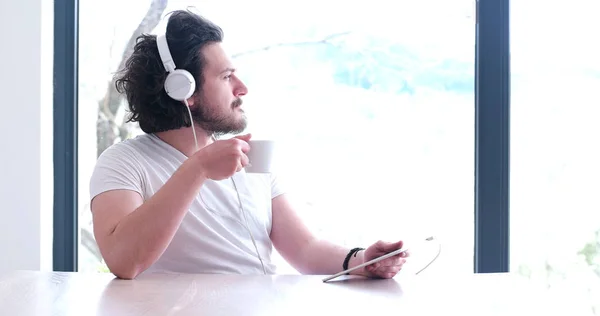 Junger Mann hört zu Hause Musik auf Tablet — Stockfoto