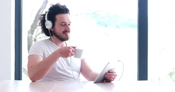 Młodego człowieka, słuchania muzyki na tablecie w domu — Zdjęcie stockowe