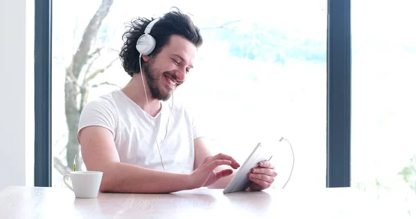 Jeune homme écouter de la musique sur tablette à la maison — Photo