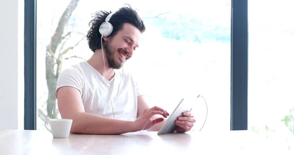 Νεαρός ακούγοντας μουσική στο tablet στο σπίτι — Φωτογραφία Αρχείου