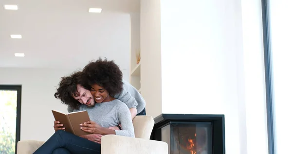 Pareja multiétnica abrazándose frente a la chimenea —  Fotos de Stock