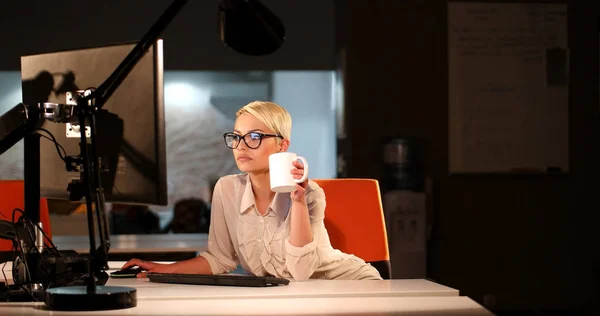 Vrouw die op de computer in donkere kantoor werkt — Stockfoto