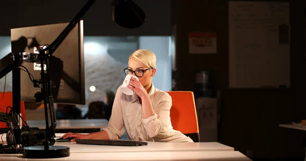 Женщина, работающая за компьютером в темном офисе — стоковое фото