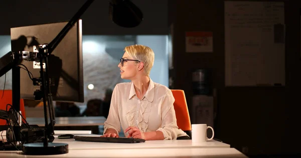 Vrouw die op de computer in donkere kantoor werkt — Stockfoto