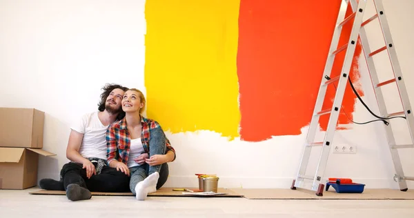 Feliz jovem casal relaxante após a pintura — Fotografia de Stock