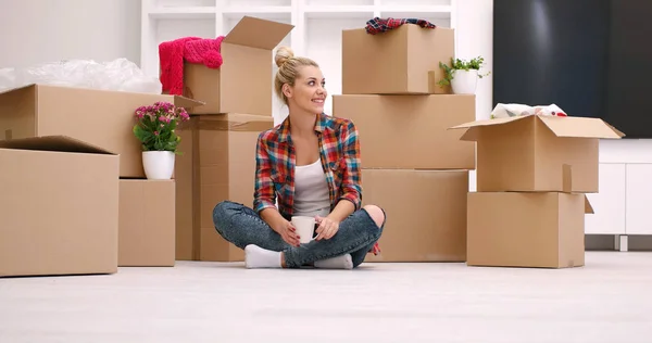 Vrouw met veel kartonnen dozen zittend op de vloer — Stockfoto