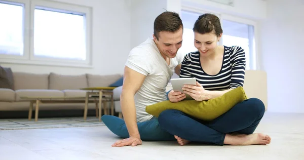 Pareja joven usando tableta digital en el suelo —  Fotos de Stock