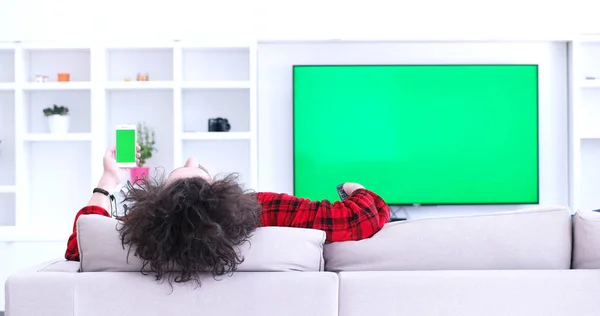 Молодой человек на диване смотрит телевизор — стоковое фото