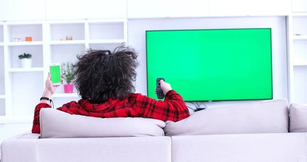 Młody człowiek na kanapie, oglądanie telewizji — Zdjęcie stockowe