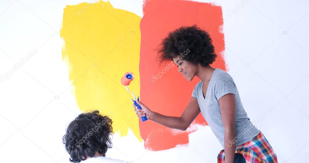 multiethnic couple painting interior wall