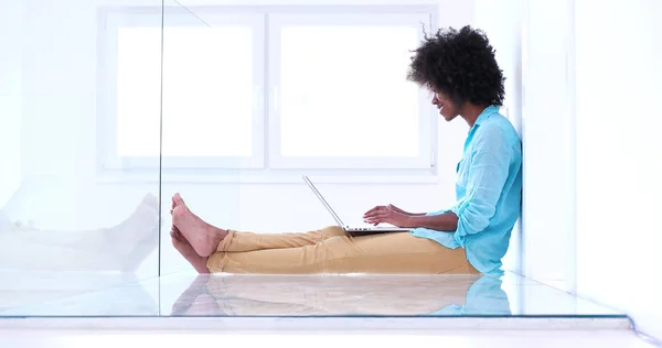 Zwarte vrouw met laptopcomputer op de vloer — Stockfoto