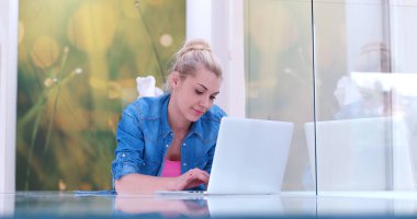 genç kadın yerde dizüstü bilgisayar kullanan