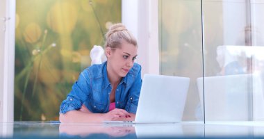 genç kadın yerde dizüstü bilgisayar kullanan