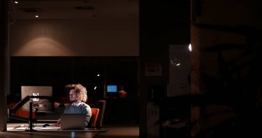 karanlık ofisinde bilgisayarda çalışan adam