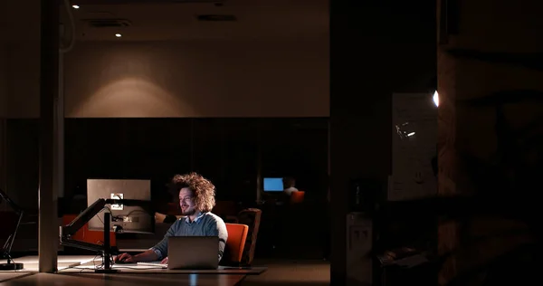 Человек, работающий за компьютером в темном офисе — стоковое фото