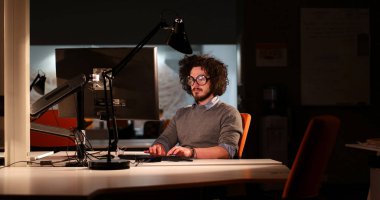 karanlık ofisinde bilgisayarda çalışan adam