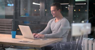 karanlık ofiste dizüstü bilgisayarda çalışan adam