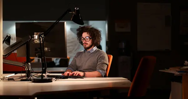 어두운 사무실에 있는 컴퓨터에서 작업 하는 남자 — 스톡 사진