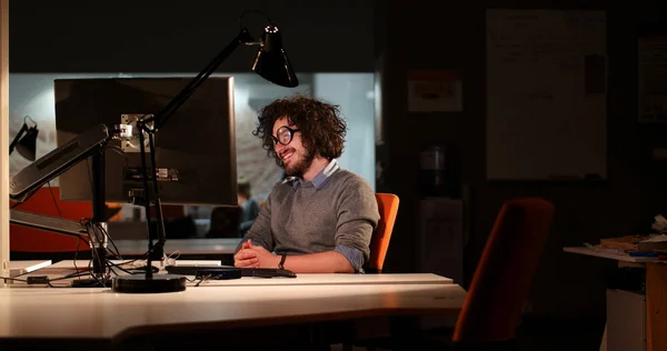 暗いオフィスにあるコンピューターで作業する人 — ストック写真
