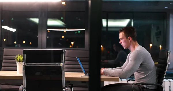 Man working on laptop in dark office — Stock Photo, Image