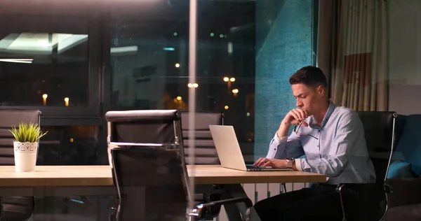 Homem trabalhando no laptop no escritório escuro — Fotografia de Stock