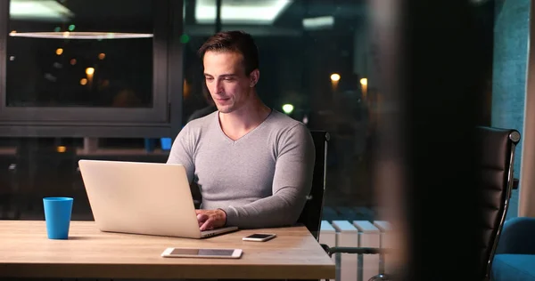 Uomo che lavora su computer portatile in ufficio scuro — Foto Stock