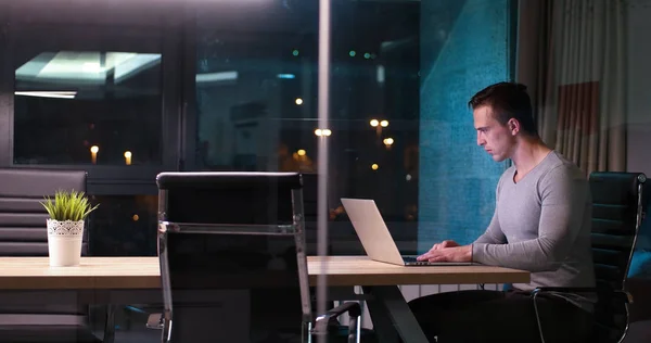 暗いオフィスでノート パソコンで作業する人 — ストック写真