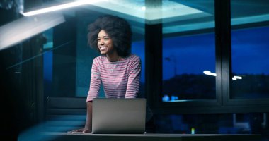 siyah işkadını gece başlangıç ofisinde bir dizüstü bilgisayar kullanarak