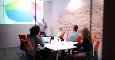 Bir grup genç iş adamı modern ofis binasında iş planlarını tartışıyor