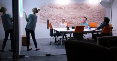 Bir grup genç iş adamı modern ofis binasında iş planlarını tartışıyor