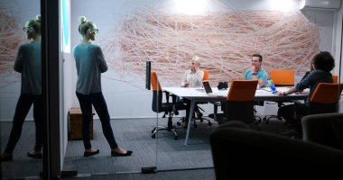 Bir grup genç iş adamı modern ofis binasında iş planlarını tartışıyor