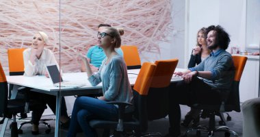 Bir grup genç iş adamı modern ofis binasında iş planlarını tartışıyor