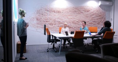 Bir grup genç iş adamı modern ofis binasında iş planlarını tartışıyor