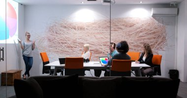 Bir grup genç iş adamı modern ofis binasında iş planlarını tartışıyor
