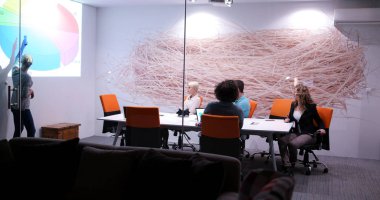 Bir grup genç iş adamı modern ofis binasında iş planlarını tartışıyor