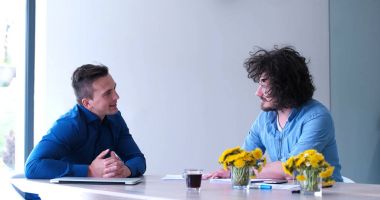 Bir grup genç iş adamı modern ofis binasında iş planlarını tartışıyor