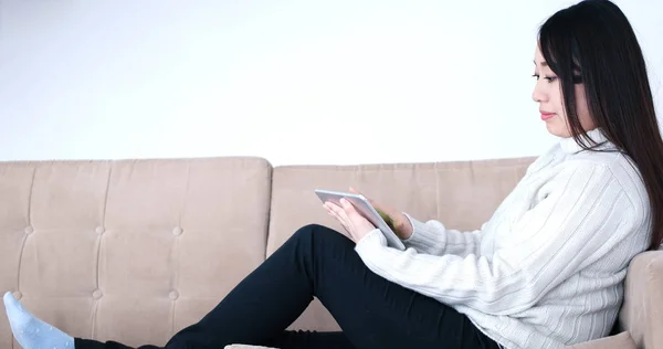 Азиатка с помощью цифрового планшета на диване — стоковое фото