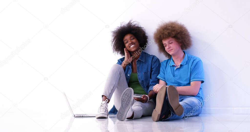 multiethnic couple sitting on the floor using a laptop and table