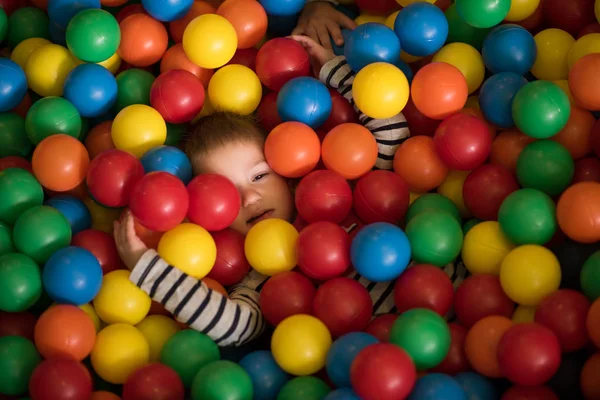 Fiú birtoklás móka, több száz színes műanyag labdák — Stock Fotó
