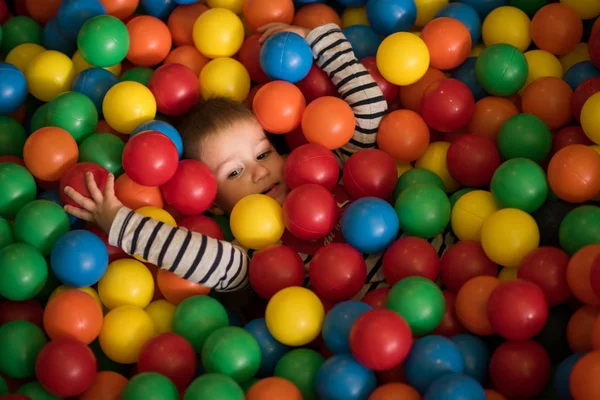 Boy having fun in hundreds of colorful plastic balls — Stock Photo, Image