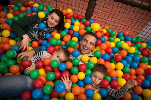 Pais jovens com crianças em uma sala de jogos infantil — Fotografia de Stock