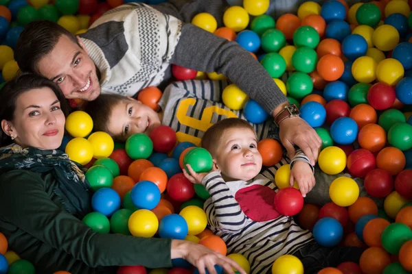 Pais jovens com crianças em uma sala de jogos infantil — Fotografia de Stock