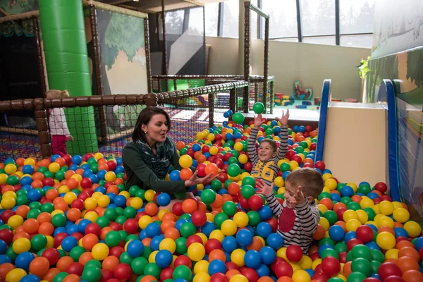 Young mom with her kids in a children's playroom — Stock Photo, Image