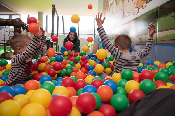 Junge Mutter mit ihren Kindern im Kinderspielzimmer — Stockfoto