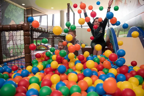 Giovane mamma con i suoi figli in una sala giochi per bambini — Foto Stock