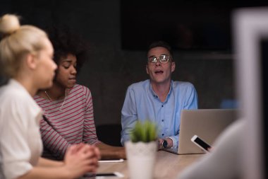 Modern gece ofis içi beyin fırtınası ve dizüstü bilgisayar üzerine çalışan çok ırklı bir girişim ekibi.