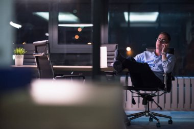 cep telefonuyla karanlık ofisinde işadamı