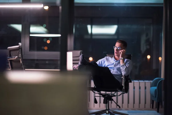 Podnikatel, používání mobilního telefonu v tmavé kanceláři — Stock fotografie